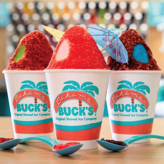 Three cups of Bahama Buck's shaved ice topped with fruit and paper umbrellas