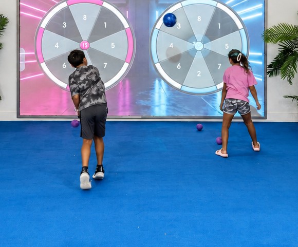 Two kids playing on the MultiBall interactive Digital Sports wall at RacFit in Buda, Texas