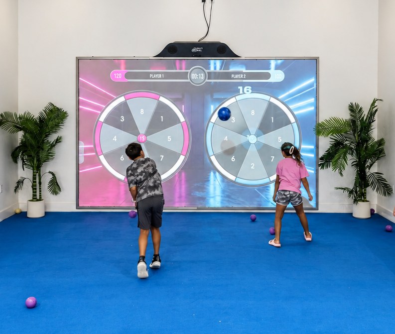 Two kids playing on the MultiBall interactive Digital Sports wall at RacFit in Buda, Texas