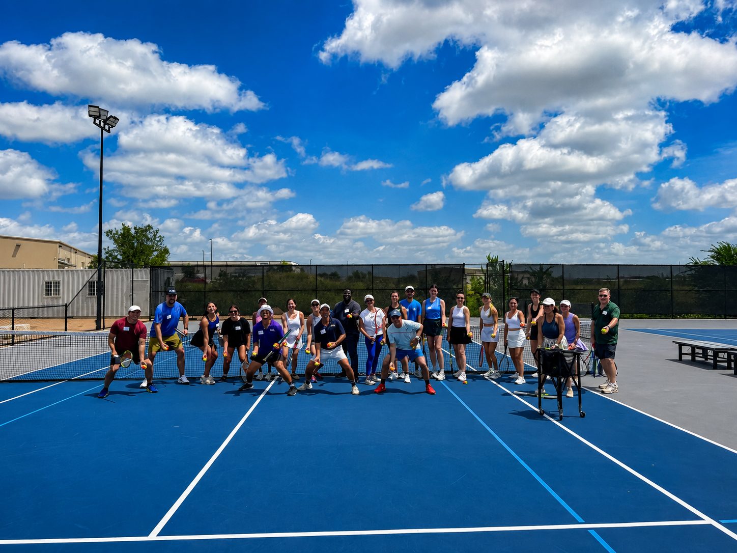 Adults on court during a group tennis clinic at RacFit in Buda, Texas
