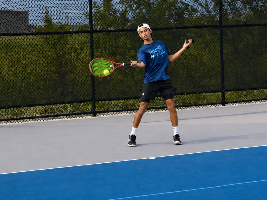 High Performance junior driving a forehand on the outdoor courts at RacFit in Buda, Texas