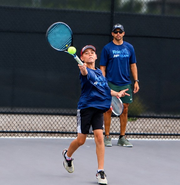 High Performance junior hitting an overhead while a coach watches at RacFit in Buda, Texas