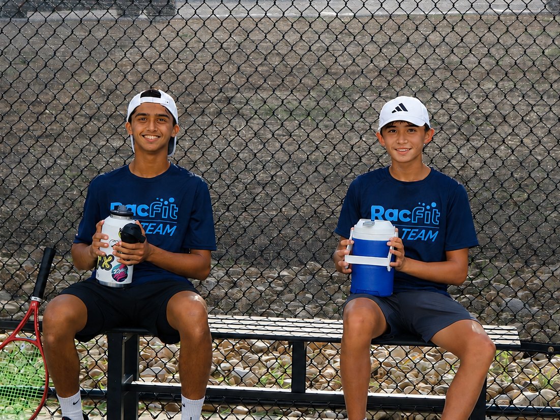 Two High Performance juniors resting courtside between drills at RacFit in Buda, Texas