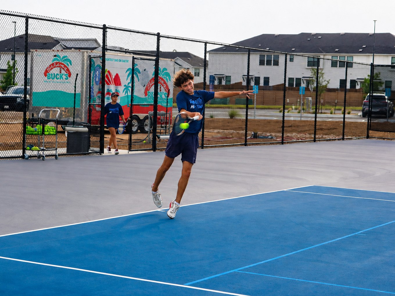 High Performance junior running down a forehand on the outdoor courts at RacFit in Buda, Texas
