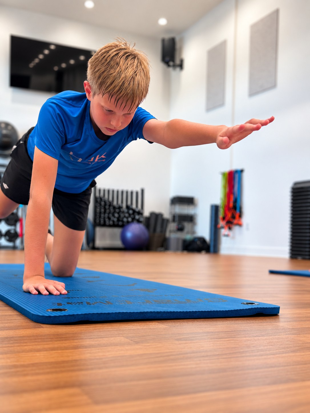 Junior player holding a bird-dog on the mat in the fitness studio at RacFit in Buda, Texas