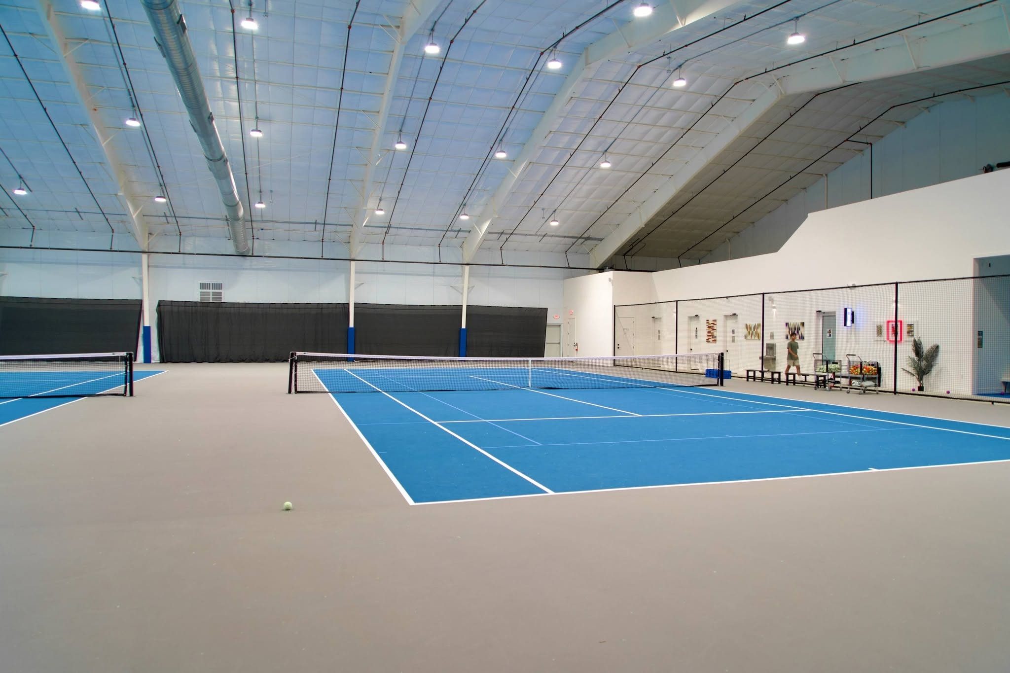 Looking across the net on the indoor tennis courts at RacFit in Buda, Texas