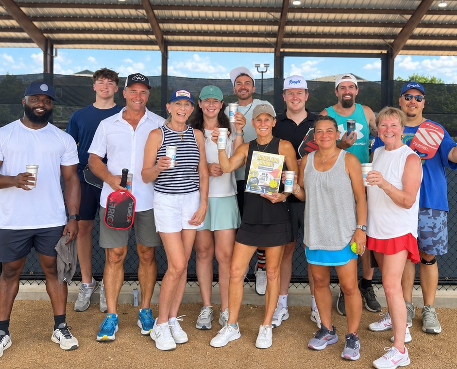Pickleball league players gathered courtside with drinks after a match at RacFit in Buda, Texas