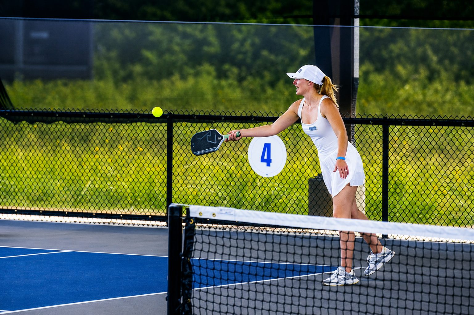 Player reaching for a shot on the covered pickleball courts at RacFit in Buda, Texas