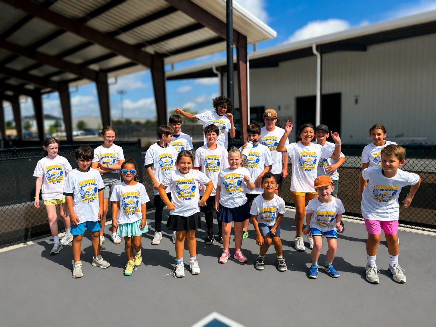 Summer Sports Camp group in RacFit camp shirts on the covered courts at RacFit in Buda, Texas