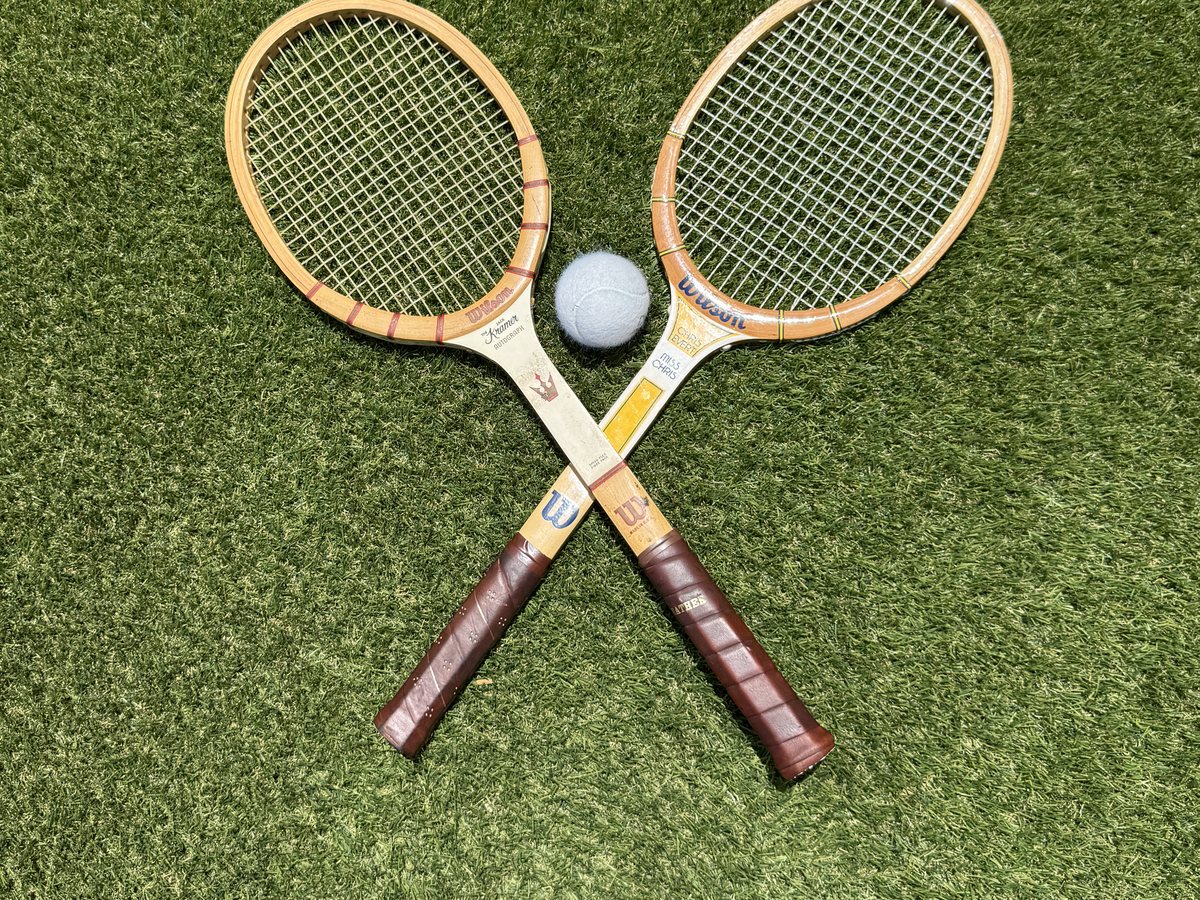 Two vintage Wilson wood racquets crossed on the turf at RacFit in Buda, Texas
