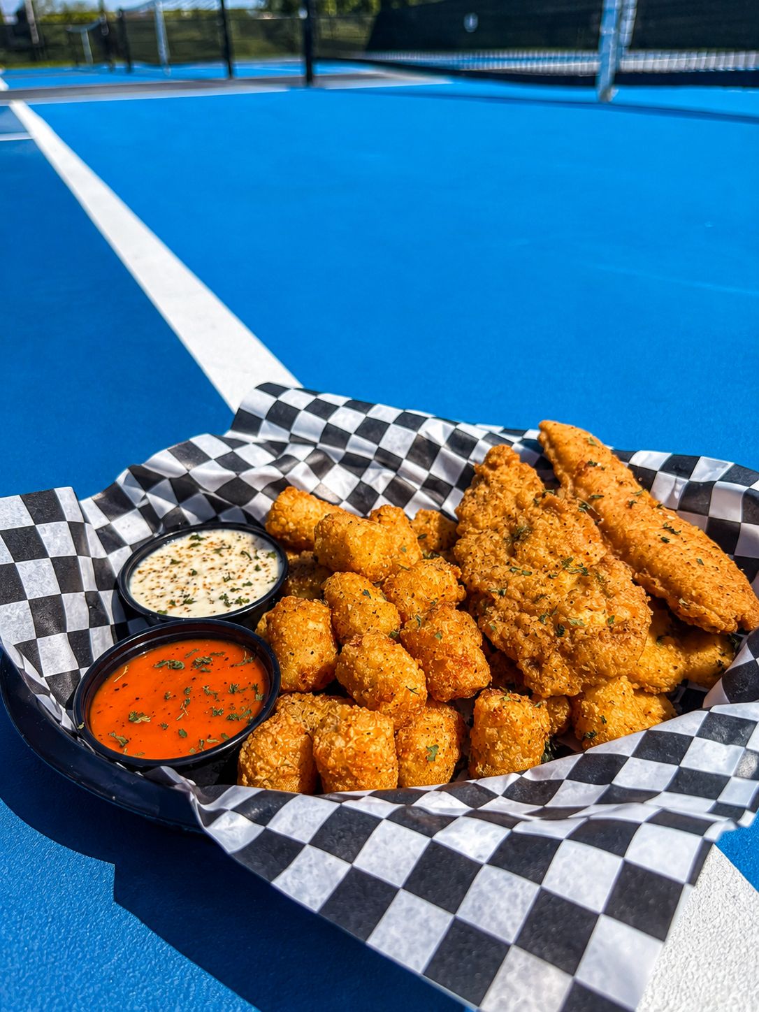 Chicken tenders and tater tots with dipping sauces courtside at RacFit in Buda, Texas