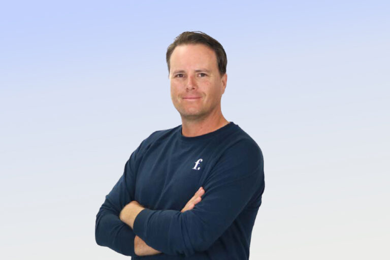 Person smiling with arms crossed in blue shirt.