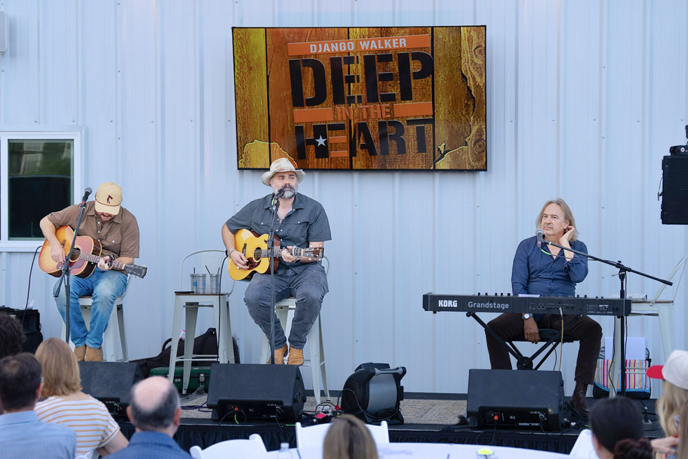 Three musicians performing on outdoor stage