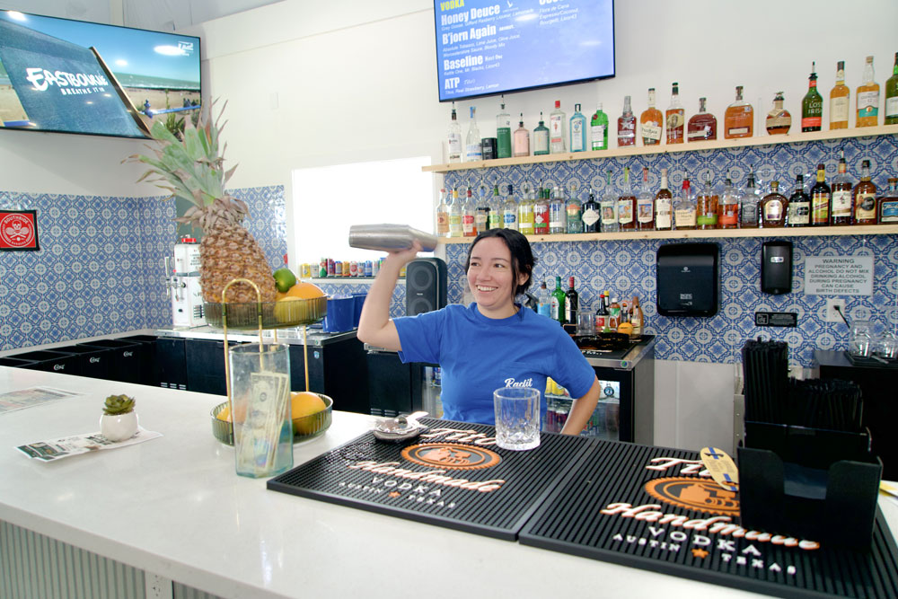 Bartender shaking cocktail behind colorful bar counter